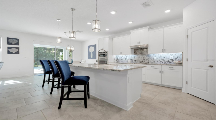 The Gorgeous Kitchen Overlooks A Casual Dining Space And Generous Family Room Complete With A Stylish Accent Wall And Sliding Glass Door Access To The Lanai, Outdoor Kitchen And Heated/Screened Pool!