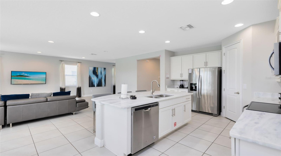 The beautiful and open kitchen is equipped with stone countertops, solid wood cabinets, stainless steel appliances, an island, a breakfast bar, an eat-in area, and all the kitchen essentials you will need for your family and future guests.
