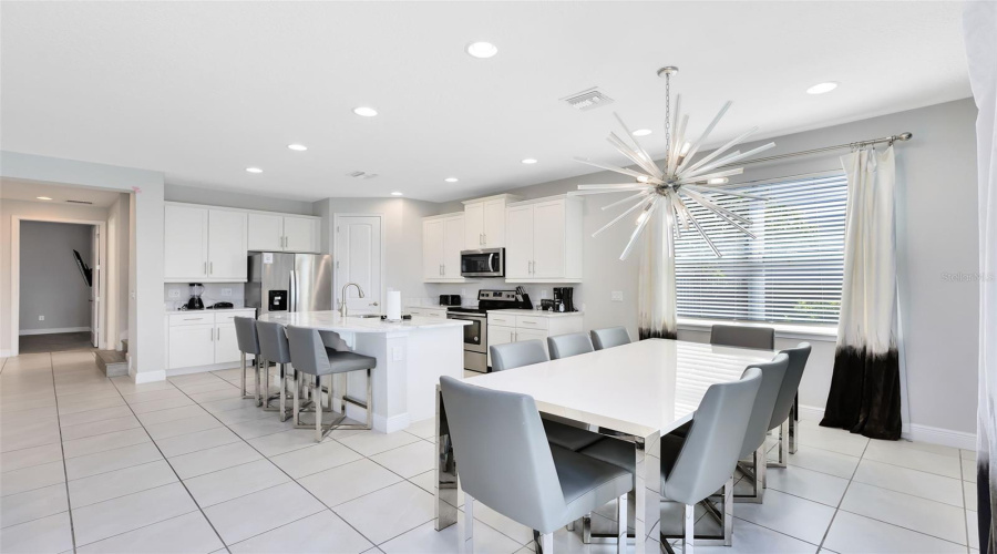 The beautiful and open kitchen is equipped with stone countertops, solid wood cabinets, stainless steel appliances, an island, a breakfast bar, an eat-in area, and all the kitchen essentials you will need for your family and future guests.