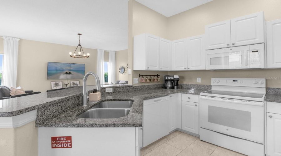 Kitchen Area Has White Appliances And Solid Stone Counters