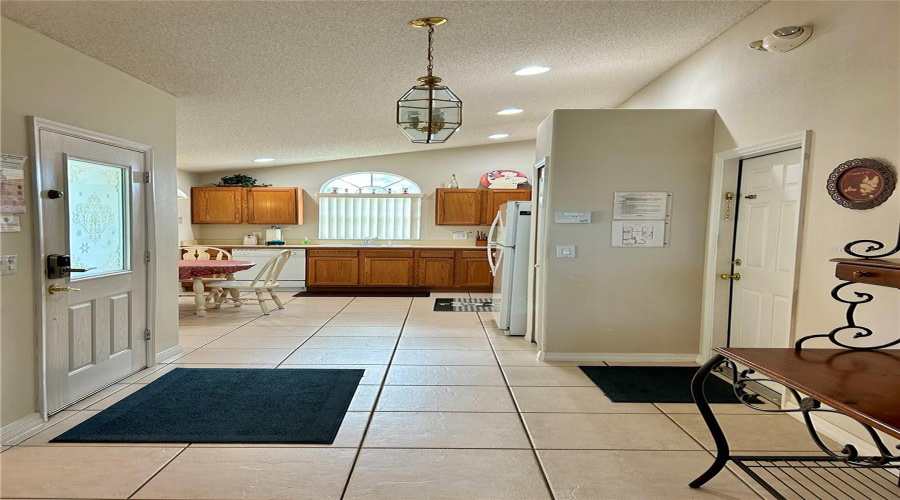 Foyer Facing Kitchen With Vaulted Ceiling And Plenty Of Natural And Recessed Lighting.