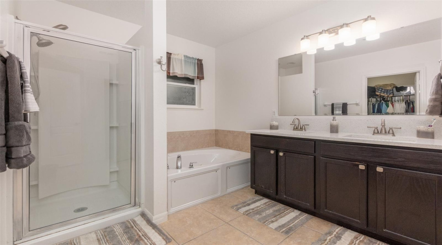 Tiled En Suite Primary Bathroom Has Double Vanity With White Quartz Counters, Walk-In Closet,  Separate Shower And Jetted Whirlpool Tub.