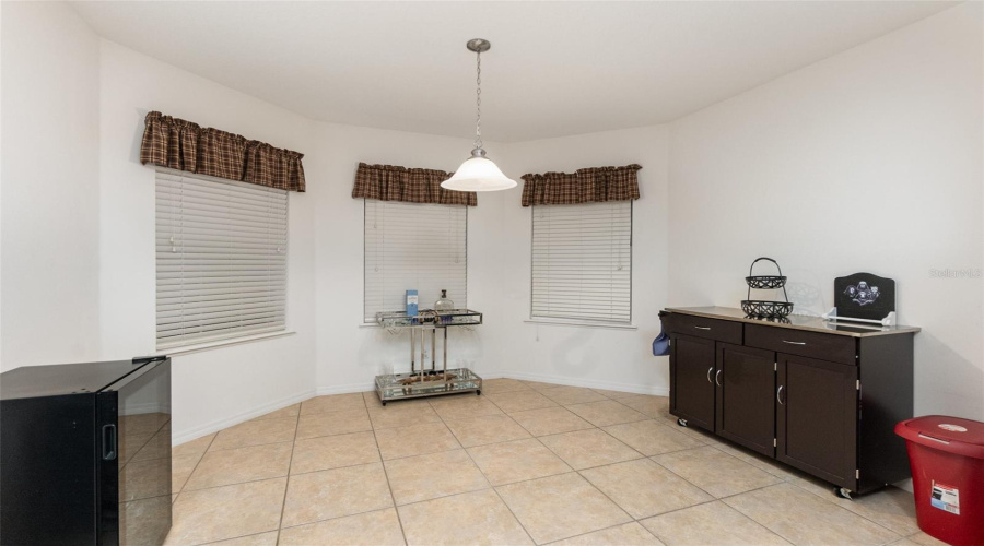 Tiled Kitchen Features White Quartz Counters And Breakfast Bar, Modern Black Appliances And Stainless Steel Dishwasher And Bay Window With Large Dinette Eating Space.