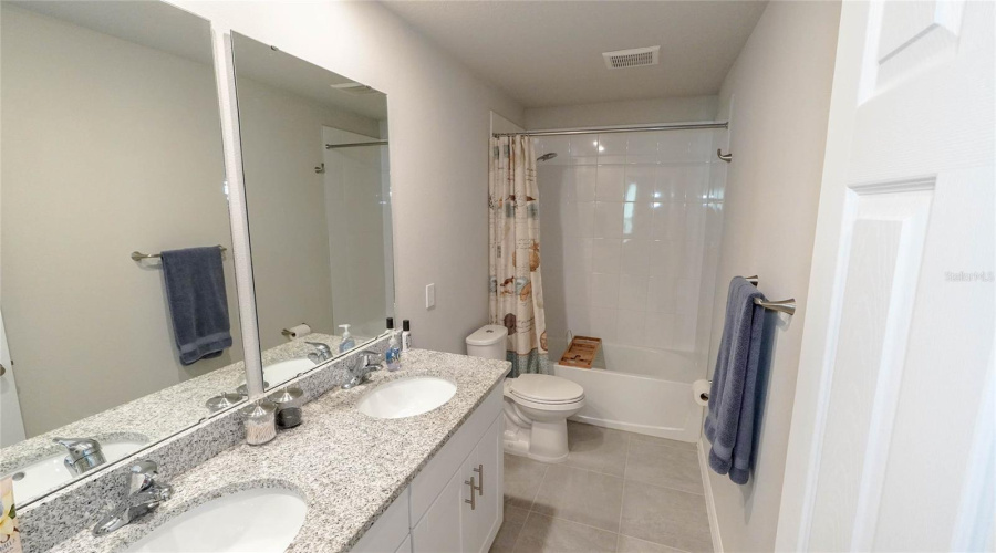 Second Floor Full Bath Features A Large Vanity With A Granite Countertop And Dual Sinks, And A Tub With Shower.