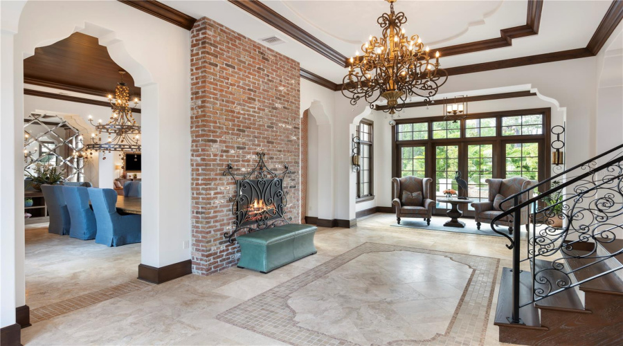 Grand foyer with fireplace and sweeping staircase separating bedrooms and living spaces