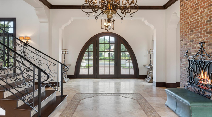 Grand foyer with fireplace and sweeping staircase separating bedrooms and living spaces