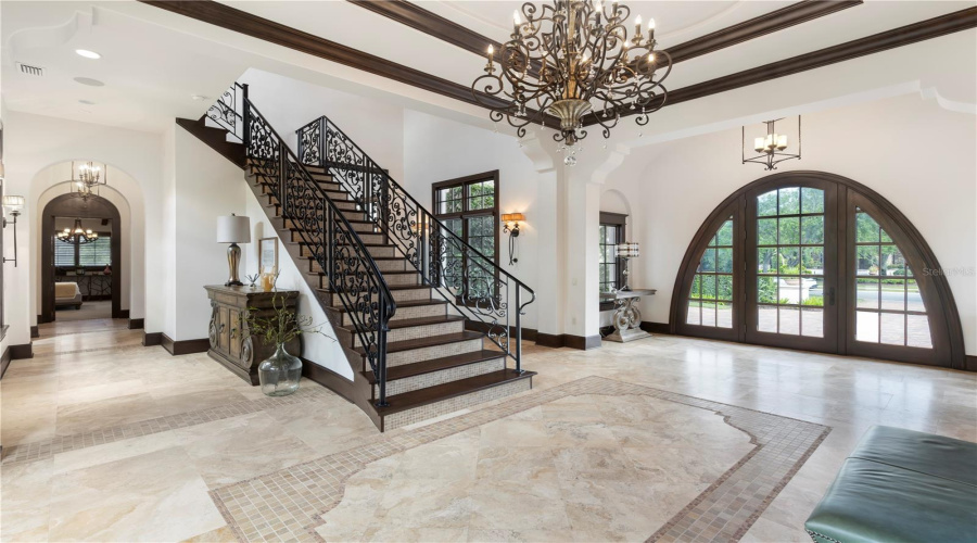 Grand foyer with fireplace and sweeping staircase separating bedrooms and living spaces