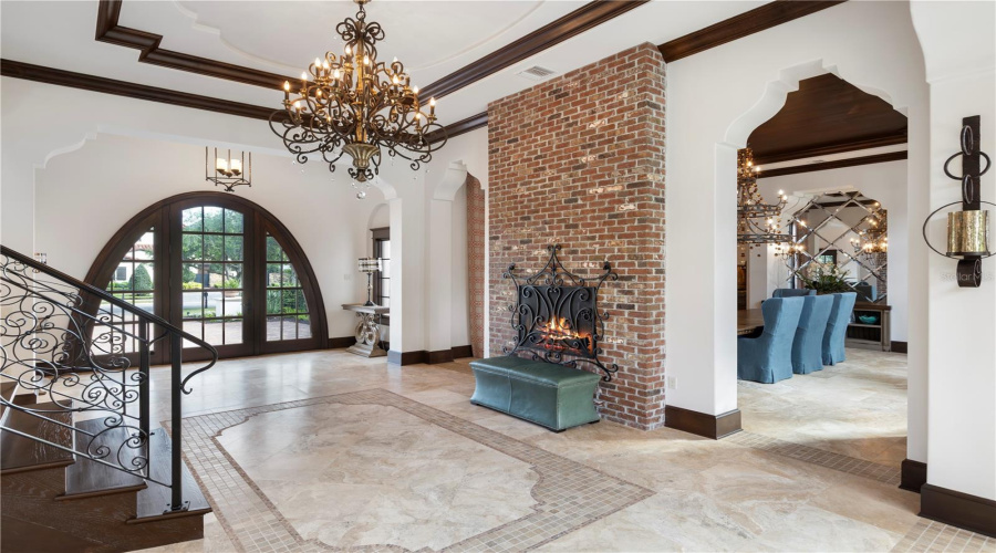 Grand foyer with fireplace and sweeping staircase separating bedrooms and living spaces