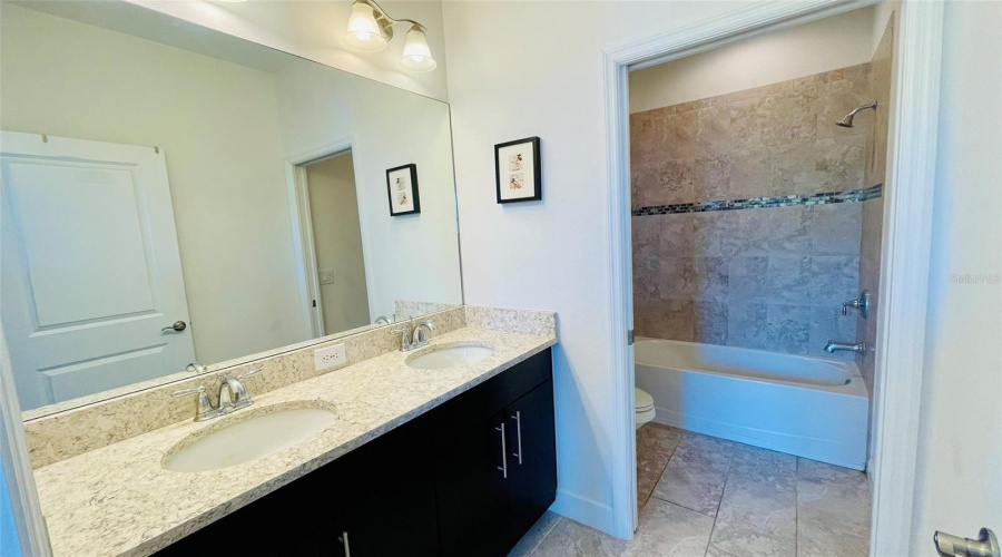 Upstairs Primary Ensuite Bathroom With Dual Sinks And Shower Tub Combo