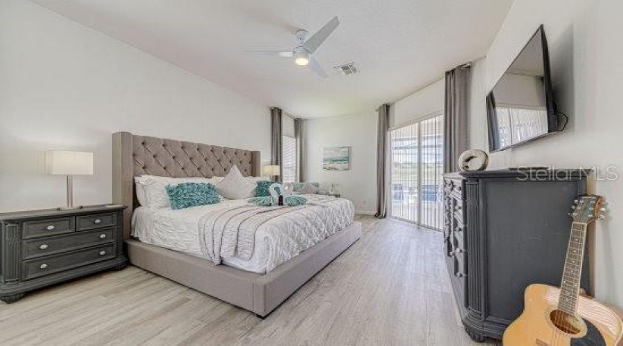 Primary Bedroom With Sliding Doors Leading To Pool Deck, With Additional Windows Giving Natural Light Throughout This Large Space.