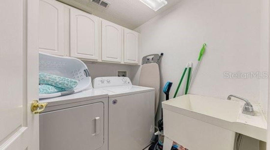 Separate Laundry Room With Additional Cabinet Storage Space And Utility Sink