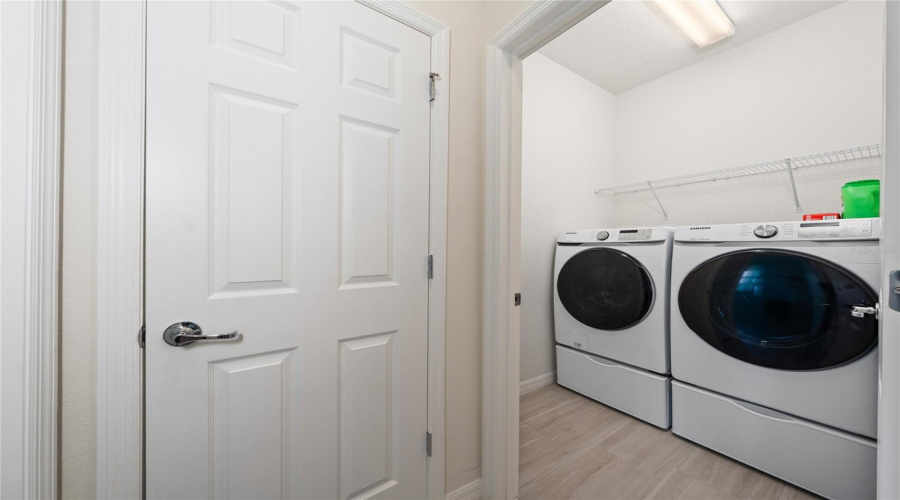 Generous Size Laundry Room With Shelving Near Primary Bedroom