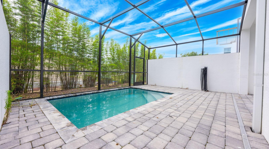 Step outside to your private oasis—a screen-enclosed in-ground pool surrounded by a generous paved patio.