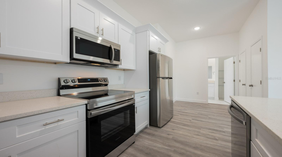 The open-concept Kitchen features white solid wood cabinets and modern sleek appliances.