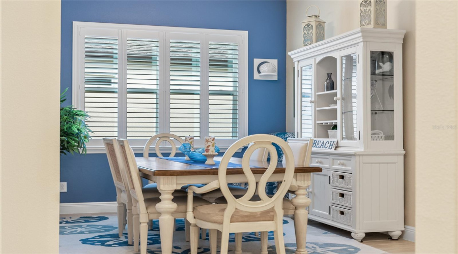 Coastal vibes flow through this bright dining space with plantation shutters and beachy charm.