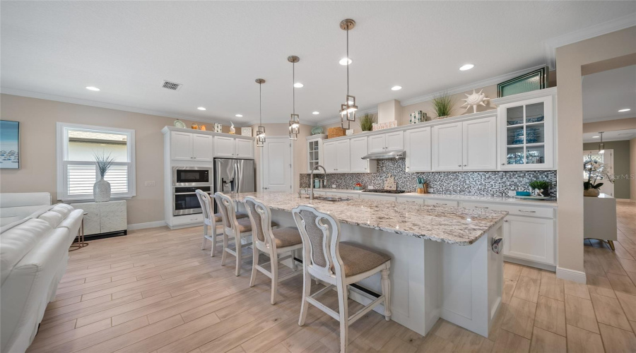 Bright and airy kitchen with a huge island, gas stove, and sleek stainless steel appliances.