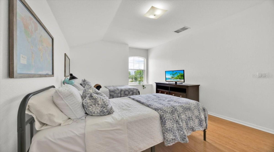 Another view of this spacious upstairs room highlights the clean lines and natural light streaming through the arched window. The layout offers flexibility for a variety of living arrangements and personal styles.Español:Otra vista de esta espaciosa habitación en la planta alta resalta las líneas limpias y la luz natural que entra por la ventana arqueada. La distribución ofrece flexibilidad para distintos usos y estilos de vida.