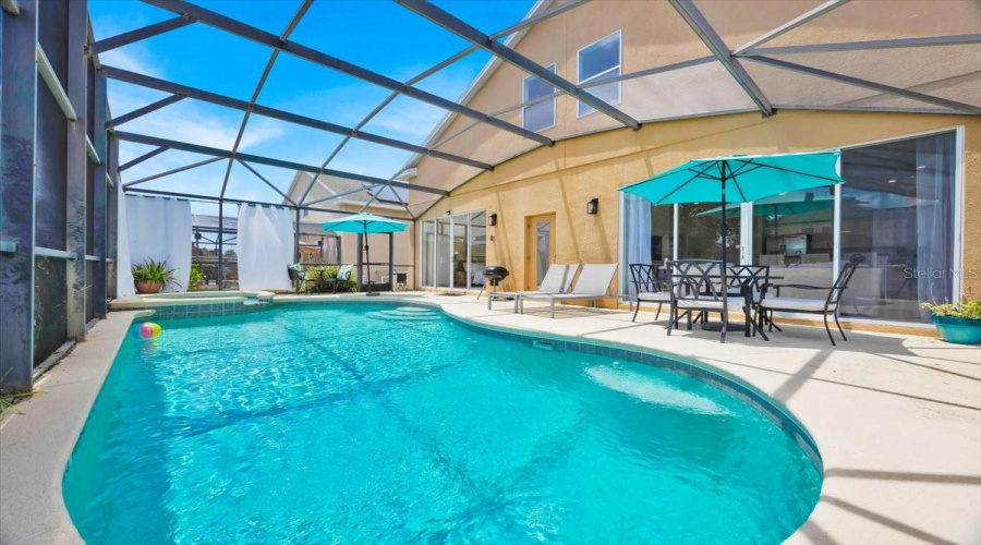 Your Private Poolside OasisThis inviting screened-in patio offers the perfect blend of relaxation and entertainment. Take a refreshing dip in the heated pool, unwind in the spa, or enjoy a meal under the umbrella with the calming sounds of water nearby. Ideal for sunny days, starlit evenings, and unforgettable vacation moments.Español:Tu Oasis Privado con PiscinaEste acogedor patio con malla brinda el equilibrio perfecto entre descanso y diversión. Disfruta de un baño refrescante en la piscina climatizada, relájate en el jacuzzi o cena bajo la sombrilla mientras escuchas el suave murmullo del agua. Ideal para días soleados, noches bajo las estrellas y momentos vacacionales inolvidables.