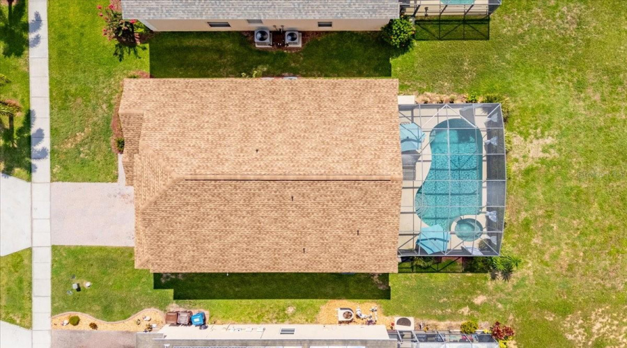 This stunning aerial view highlights the newer roof, beautiful landscaping, and peaceful surroundings in a gated community.Español:Esta vista aérea resalta el techo más reciente, el hermoso paisajismo y la tranquilidad de esta comunidad cerrada.