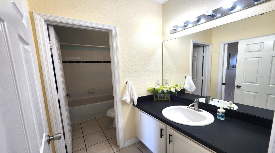 Upstairs Master Bathroom:This thoughtfully designed bathroom features a private shower/tub combo and toilet, separated from the vanity area for added functionality. Ideal for shared use, it also includes an exterior door for convenient access when needed—perfect for guests or family members.ESPAÑOL:Baño Principal en el Segundo Piso:Este baño bien distribuido ofrece una combinación de bañera/ducha y sanitario en un área privada, separada del tocador para mayor comodidad. También cuenta con una puerta exterior que permite el acceso cuando se requiere—ideal para visitas o el uso compartido en familia.