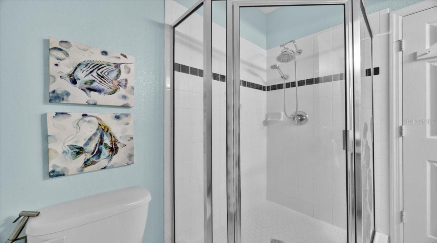 Walk-In Shower – Upstairs Shared Bathroom:This spacious walk-in shower features crisp white tile accented with a modern black trim, offering a clean and contemporary look. The glass enclosure, rain-style showerhead, and built-in shelf provide both style and function in this bright upstairs bath.ESPAÑOL:Ducha Tipo Walk-In – Baño Compartido en el Segundo Piso:Esta ducha amplia tipo walk-in cuenta con azulejos blancos y un elegante borde negro, brindando un estilo limpio y moderno. La mampara de vidrio, el cabezal tipo lluvia y el estante incorporado combinan diseño y funcionalidad en este baño luminoso del segundo piso.