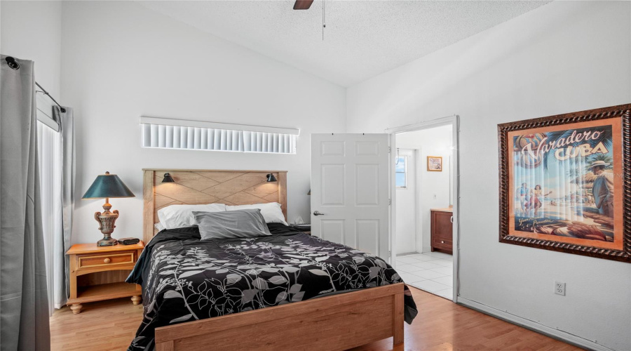 The primary bedroom has a lot of natural light with a window over the bed and a sliding glass door.