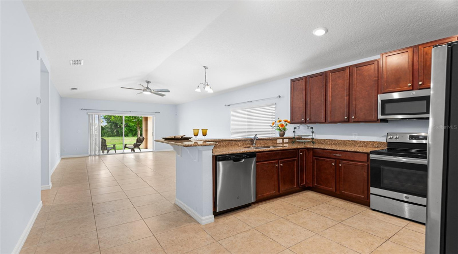 VIEW TOWARDS KITCHEN AND GREAT ROOM/FAMILY ROOM. SLIDING GLASS DOORS LEAD TO COVERED LANAI