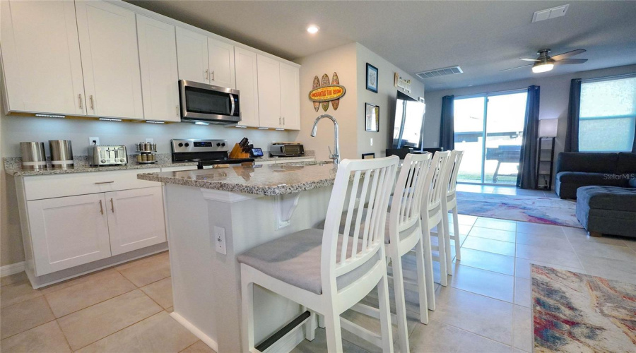 Lovely kitchen has 42" wall cabinets with crown moulding, a large island with eating area, lots of beautiful granite countertop space, accent lighting - and more!