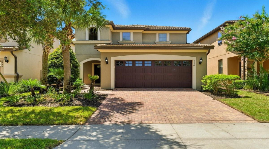 Tropical escape vibes from the moment you arrive — swaying palms, sun-kissed exterior, and a paver driveway that says welcome to vacation.