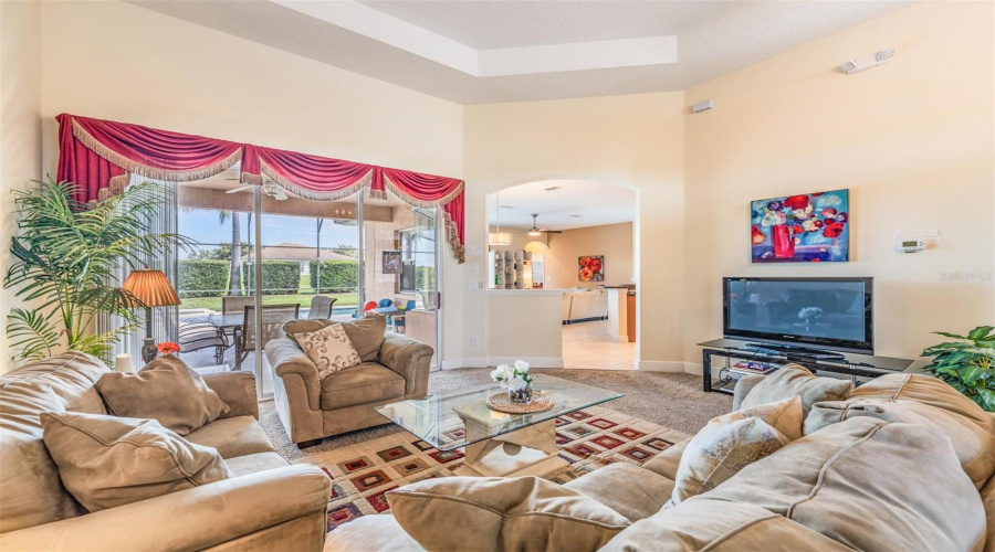 Overlooking the covered lanai and pool, the living room also provides a view into the kitchen and great room.