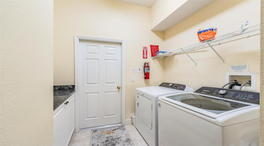 The indoor laundry room offers ample space for folding, along with shelves and cabinets for organized storage.