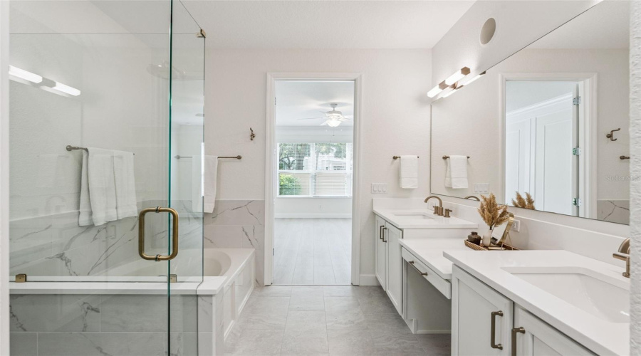 The master bath also features a soaking tub and modern brushed gold finishes and fixtures.