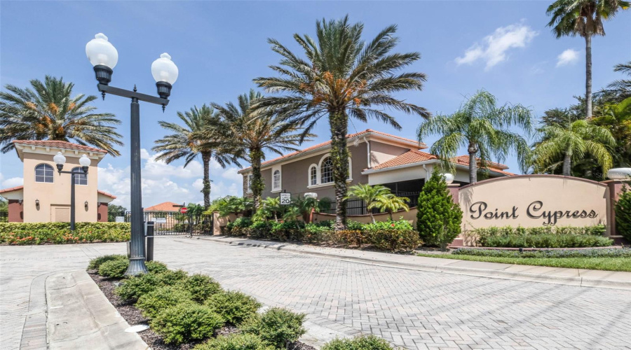 Welcome to Point Cypress, a gated townhome community featuring a beautifully landscaped entrance with tropical palms, Mediterranean-style architecture, and 24-hour secured access.