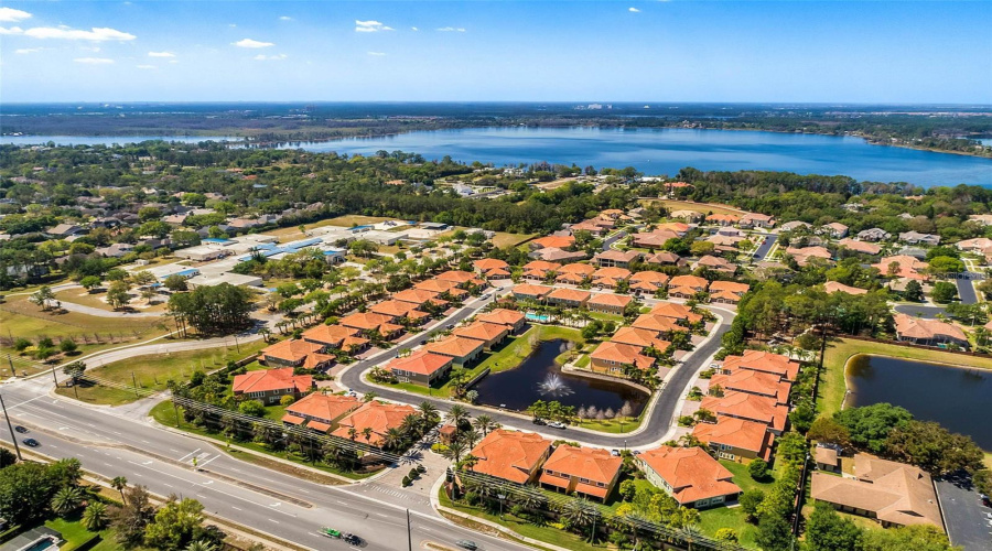 Stunning aerial view showcasing the beautifully landscaped community, sparkling pool, and nearby lakes.