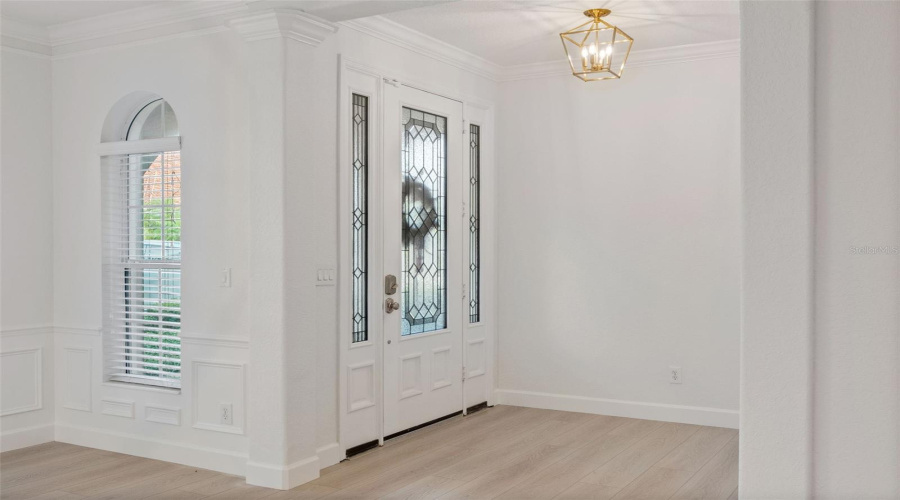 Elegant entry with decorative glass doors, crown molding and upgraded light fixture.