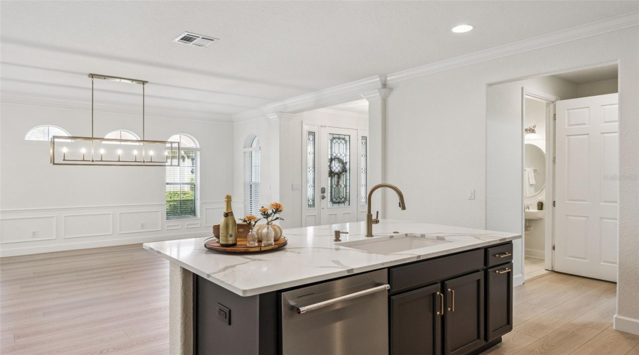 The kitchen also features stone countertops, brushed gold hardware, and a large contrasting island for entertaining and serving guests.