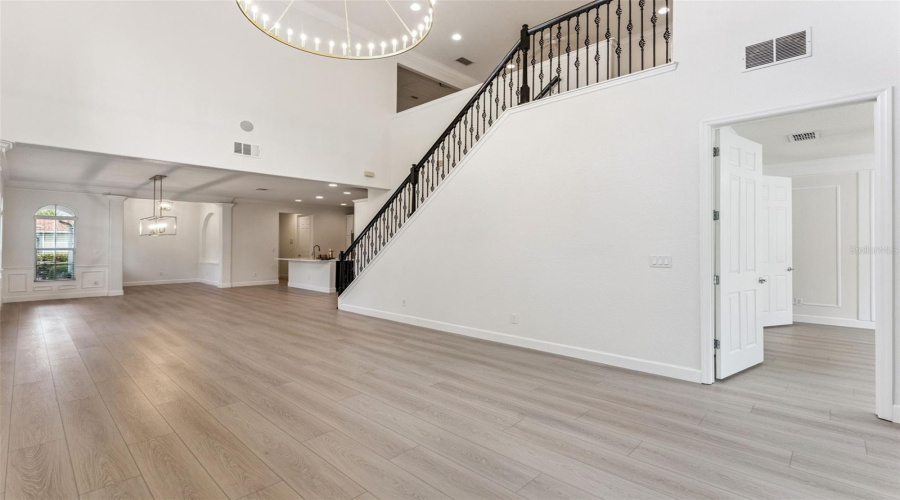 Open concept living/dining area with soaring ceilings, abundant natural light, new LVP flooring, and an elegant upgraded light fixture.