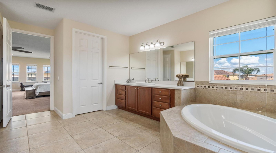 Spa inspired en-suite master bath with separate dual vanities, garden tub and separate shower and bathrooms stalls