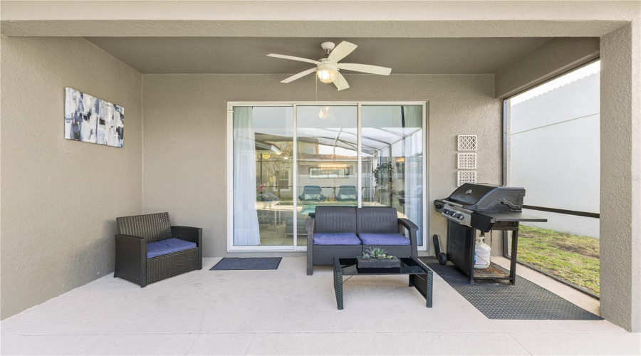 Back porch with seating are, fan and BBQ.