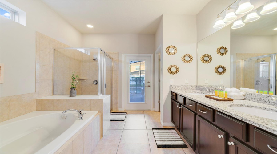 A SPA-INSPIRED EN SUITE BATH offering dual sinks, a garden tub, step-in shower, and private water closet presents an ideal retreat for owners or guests.