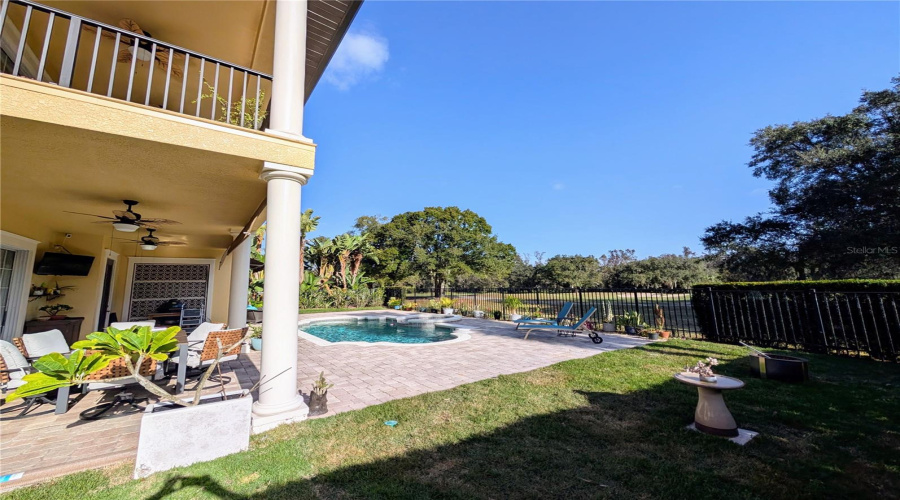 a large lot with grass on each side of pool deck