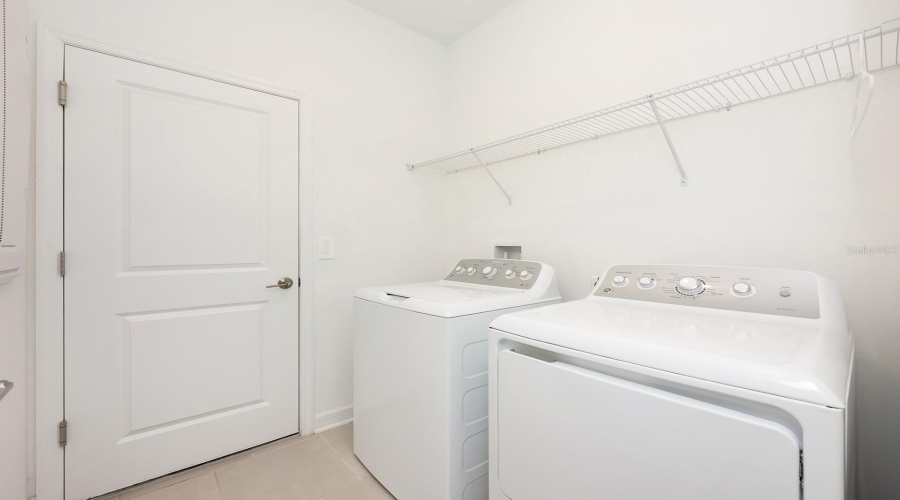 The functional Laundry Room, complete with washer, dryer and a shelf for storing supplies.