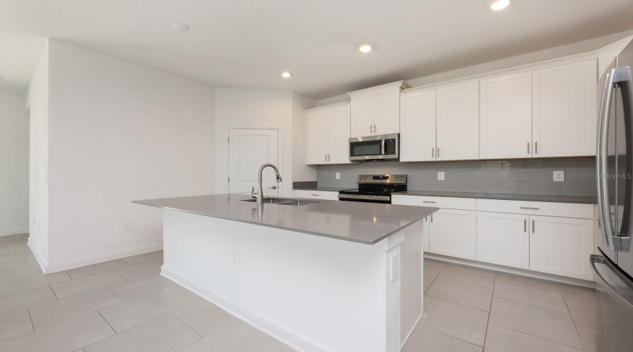 The center island includes space for counter-height seating, perfect for casual dining or conversation.