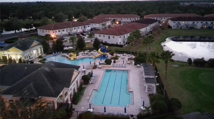 Providence Community lap pool, slides, splash beach walk in area, gym, clubhouse at dusk.