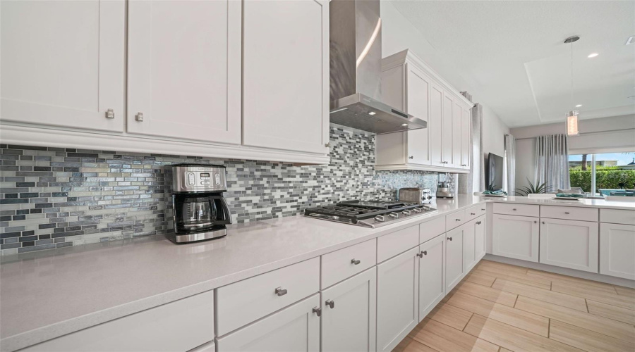 The chef’s kitchen featuring a gas cooktop with exterior-vented hood, built-in oven and microwave, refrigerator, dishwasher, and an expansive center island with generous seating.