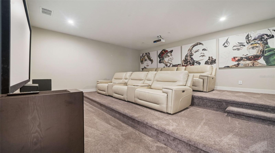 Designed for entertainment, the home includes a game room and a private theater with tiered seating, projection screen, ceiling-mounted projector, and surround sound, delivering an authentic in-home cinema experience.