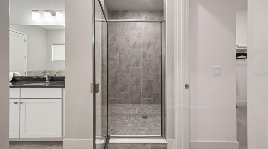 The upstairs primary bedroom features a private balcony overlooking the resort-style backyard, an ensuite bathroom with dual vanities, a separate soaking tub, a walk-in shower, and a spacious walk-in closet.