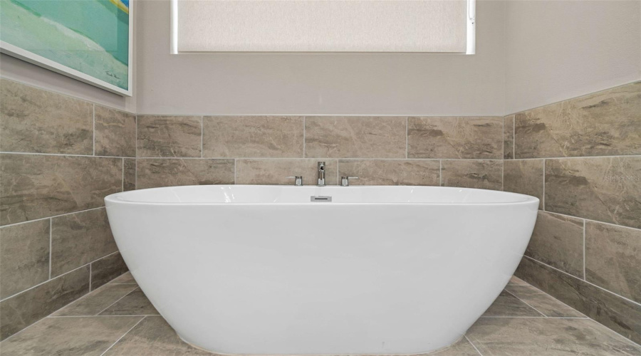 The upstairs primary bedroom features a private balcony overlooking the resort-style backyard, an ensuite bathroom with dual vanities, a separate soaking tub, a walk-in shower, and a spacious walk-in closet.