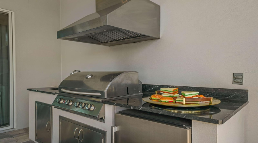 This resort-style backyard is a private oasis with a heated custom pool, raised spa, paver deck, lush landscaping, and striking fire bowls. A covered lanai with a summer kitchen and outdoor TV, plus a second-story balcony overlooking the pool, create the perfect setting for relaxation and entertaining from day to night.