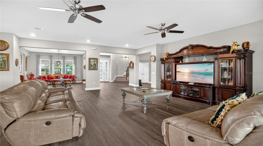 Spacious main living area with wide-plank flooring, ceiling fans, and open sightlines to adjoining rooms.